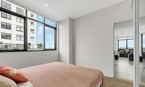 A modern bedroom with a large window, a bed with a pink blanket, and a view of a cityscape. - KozyGuru | Fairfield | Stylish Stay Near Station (Fairfield)