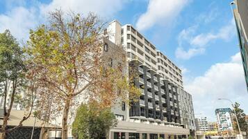 A multi-story building with balconies, a flat facade, and a clear sky.