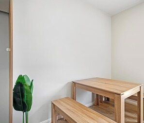 A room with a wooden table and bench, a green plant, and a white wall. - KozyGuru | Cobbitty | Serene Granny Flat Escape (Cobbitty)