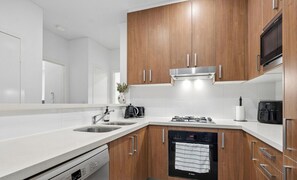 Eine moderne Küche mit Holzschränken, einer Edelstahl-Dunstabzugshaube, einem Geschirrspüler und einem Einbauofen.