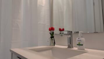 A bathroom with a white sink, a mirror, and a bottle of Equate Aloe Vera hand soap.