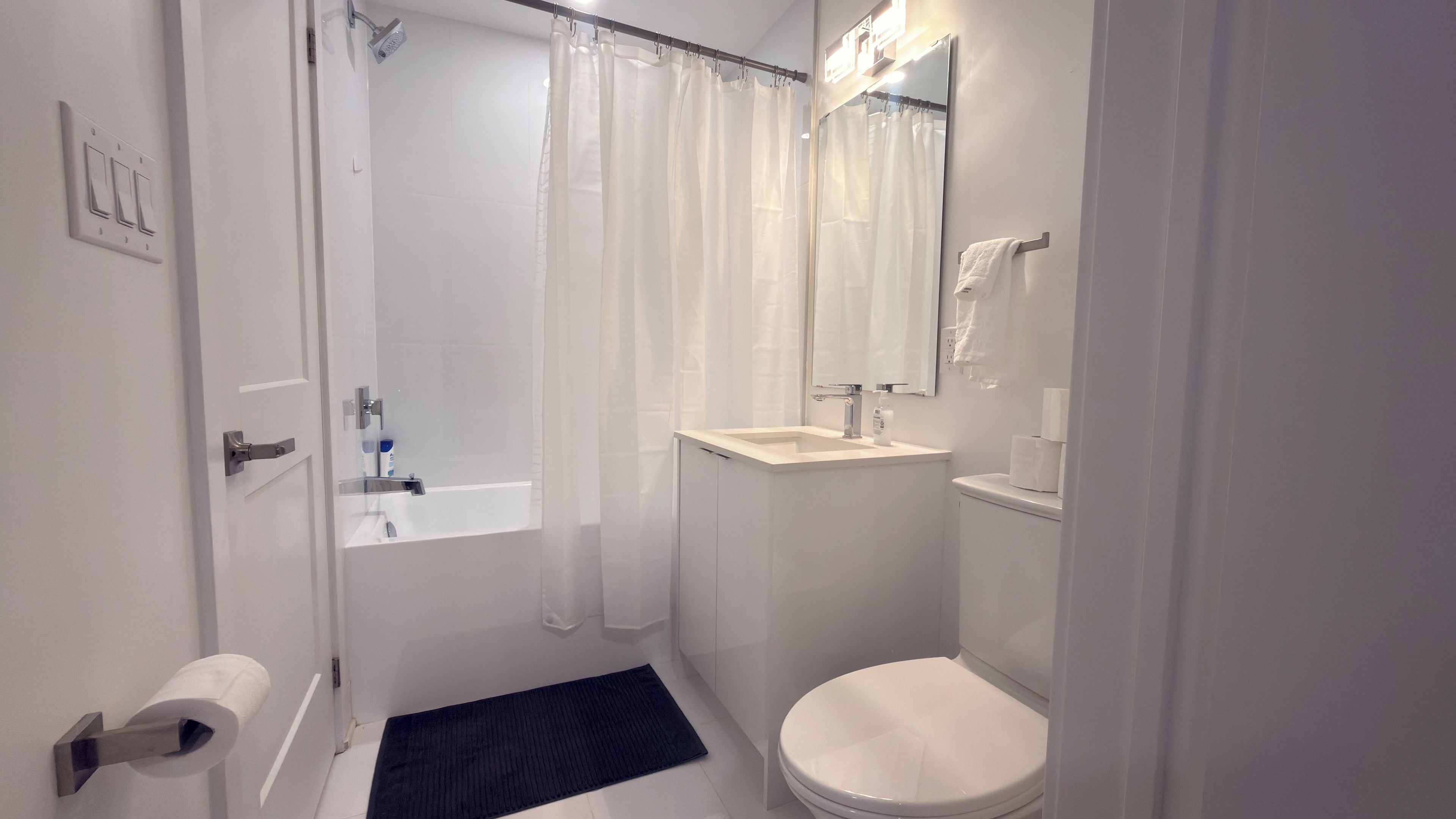 A bathroom with a bathtub, toilet, sink, and a shower curtain.