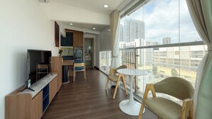 A modern living room with a television, seating area, and a view of the cityscape. - Quynh Khang Apartments & Hotels (Ho Chi Minh)