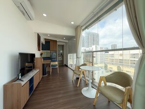 A modern living room with a television, seating area, and a view of the cityscape. - Quynh Khang Apartments & Hotels (Ho Chi Minh)