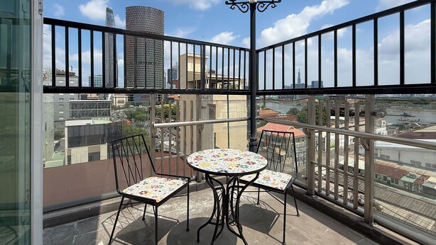 A balcony with a table and chairs, a railing, and a view of the cityscape. - Quynh Khang Apartments & Hotels (Ho Chi Minh)