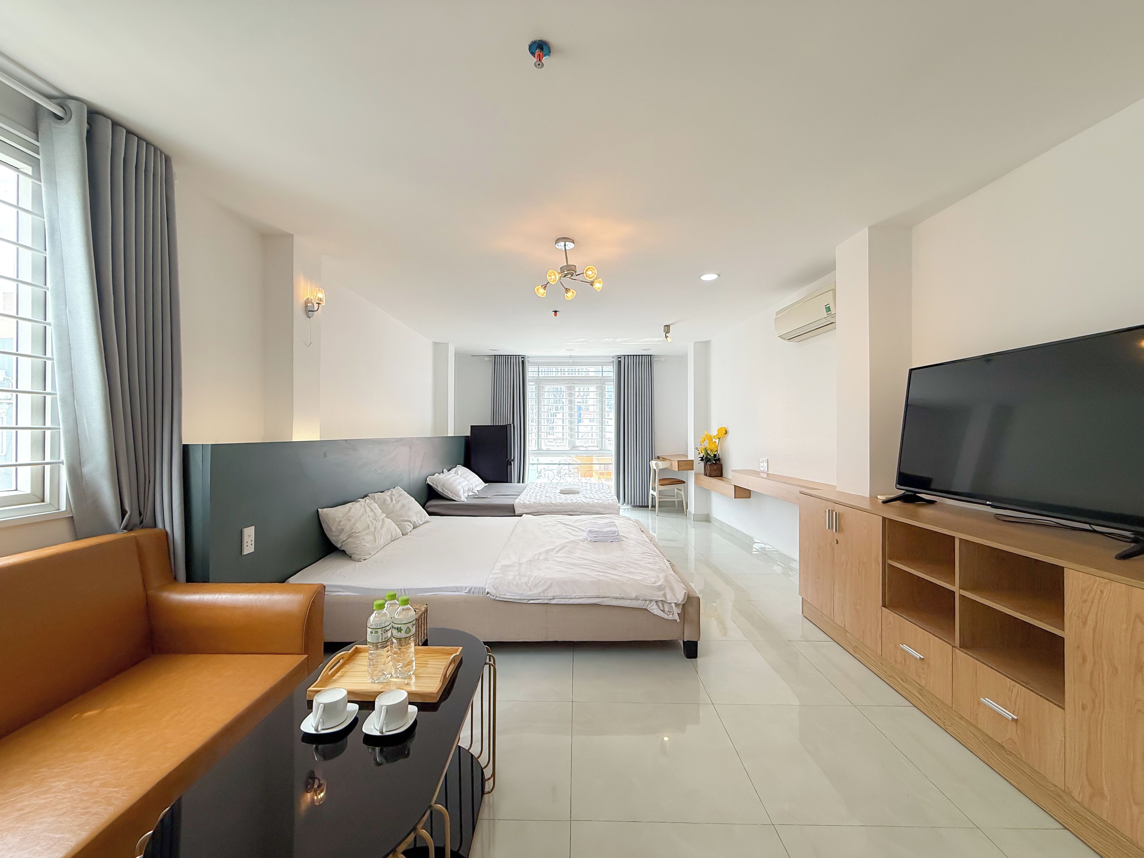 Ein modernes Hotelzimmer mit einer Couch, einem Bett, einem Fernseher und einer Essecke.