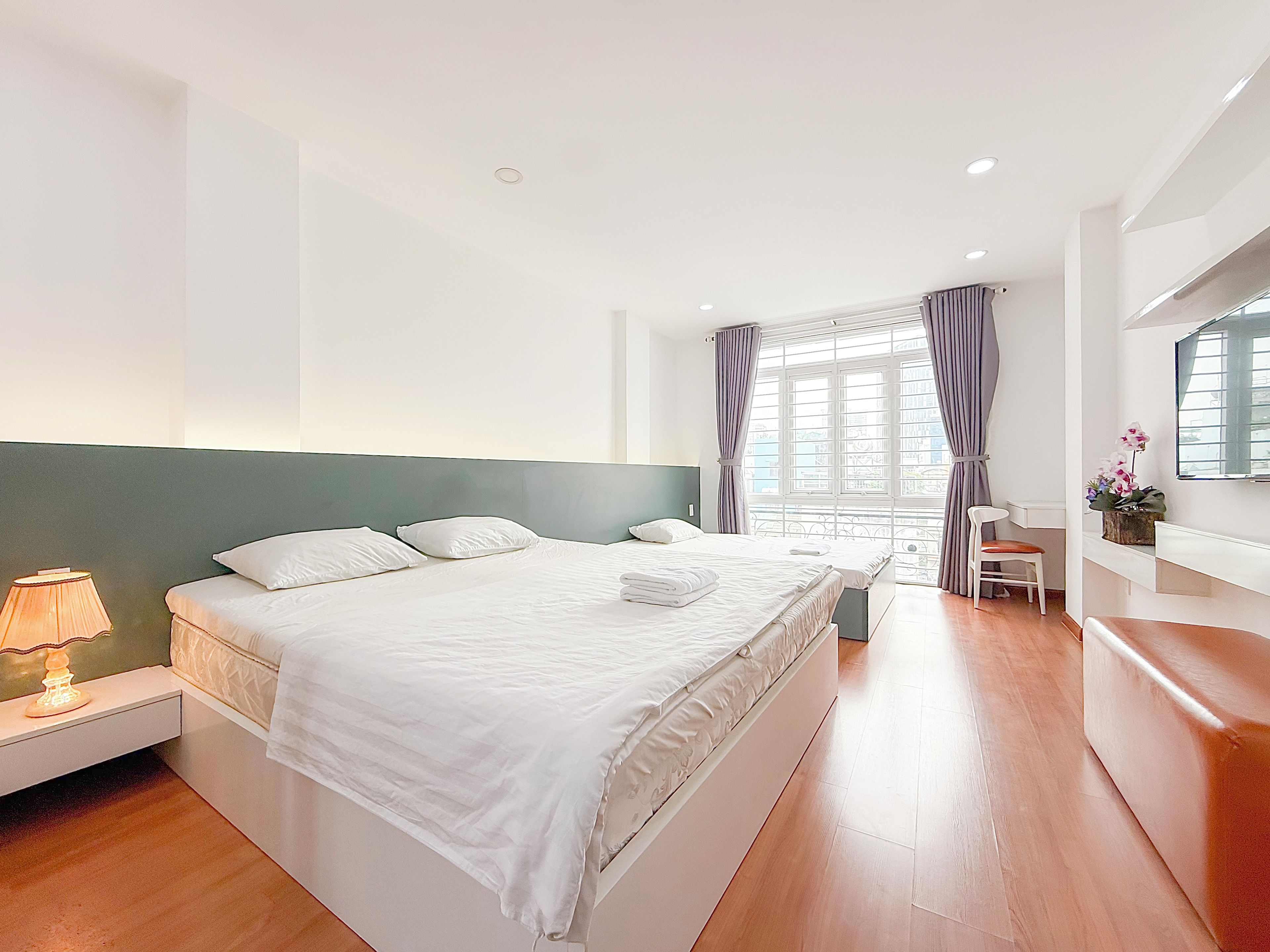 A hotel room with a large bed, bedside tables, a desk, and a chair.