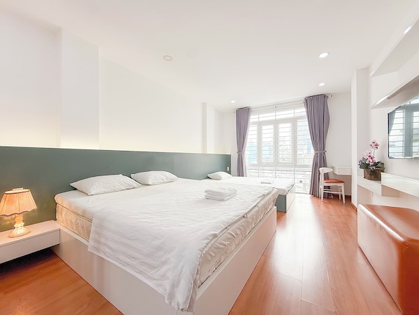 A hotel room with a large bed, bedside tables, a desk, and a chair.