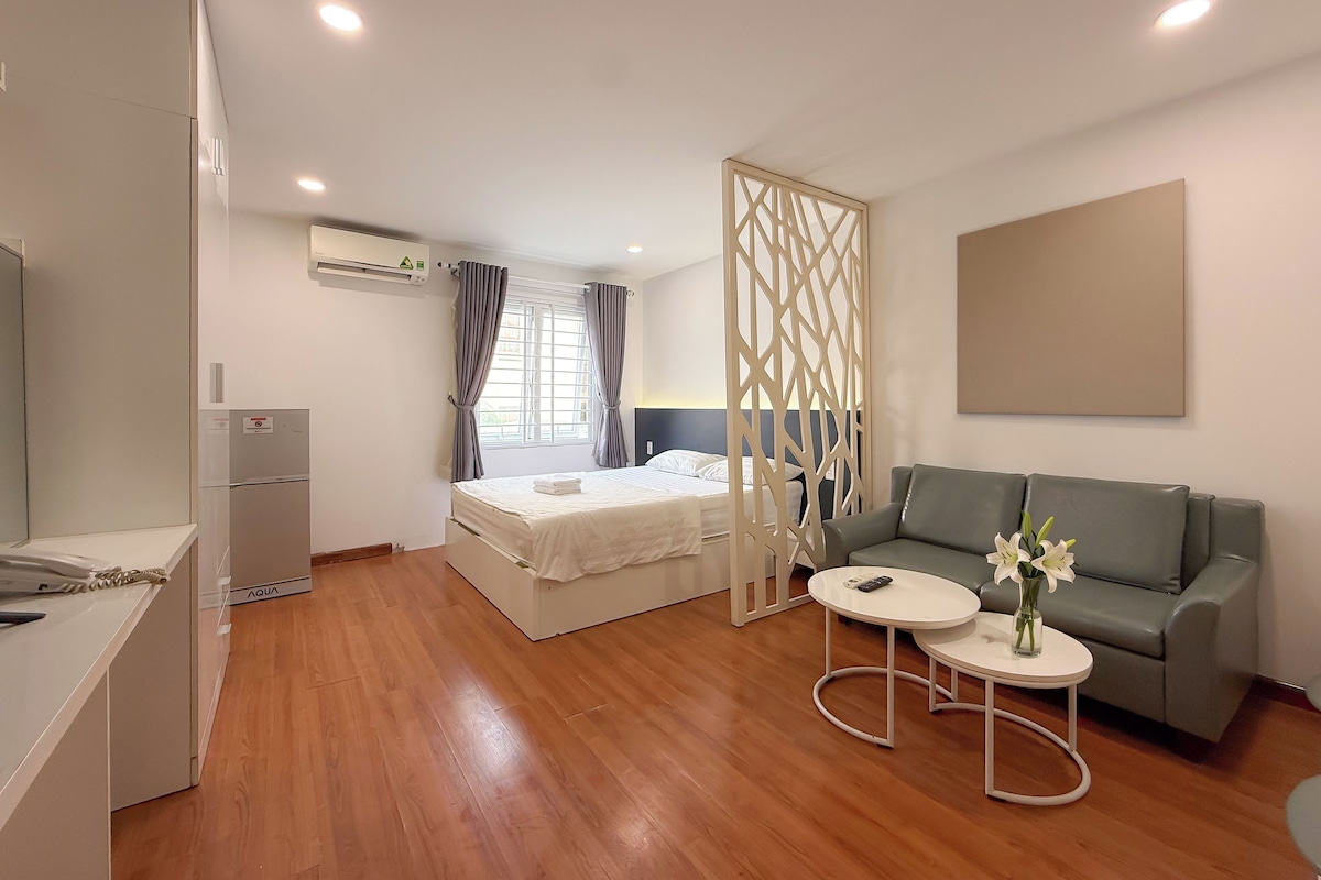 A modern hotel room with a bed, a sofa, a small table, and a decorative partition.