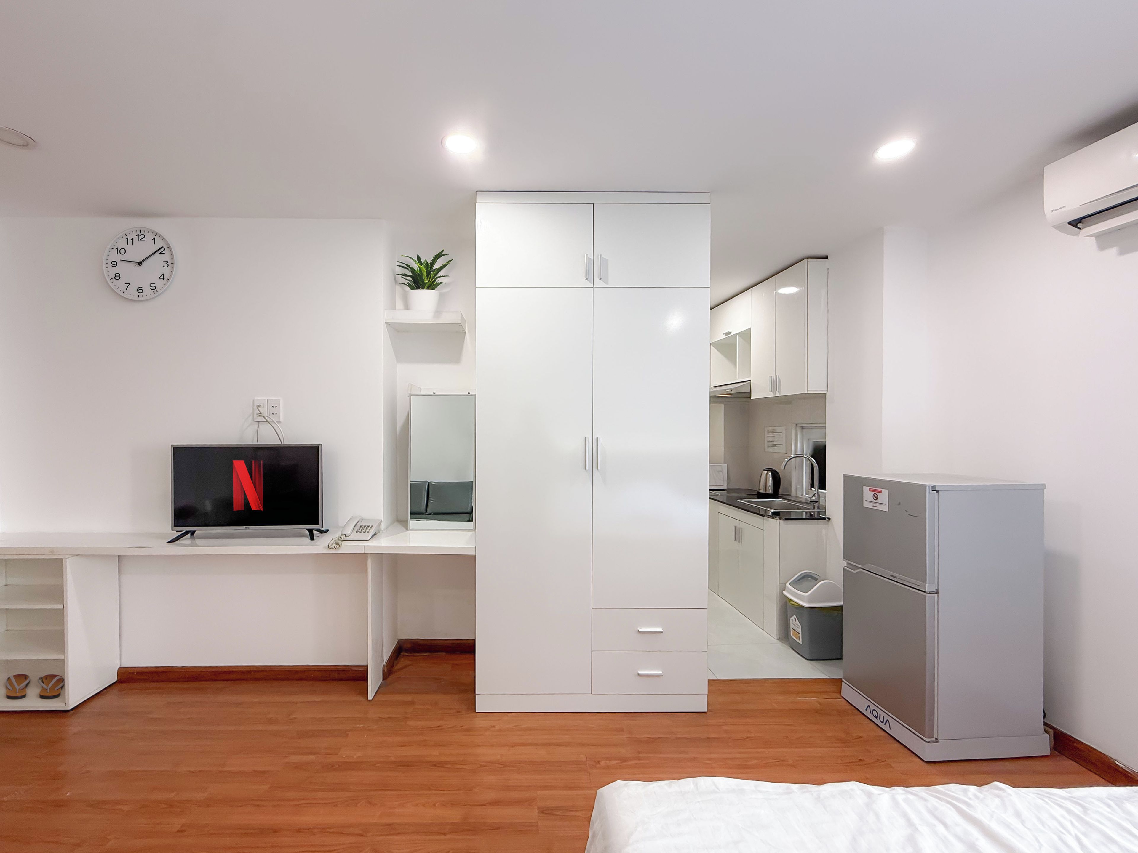 Un dormitorio moderno con cama, televisor, armario y kitchenette.