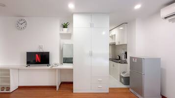 Un dormitorio moderno con cama, televisor, armario y kitchenette.