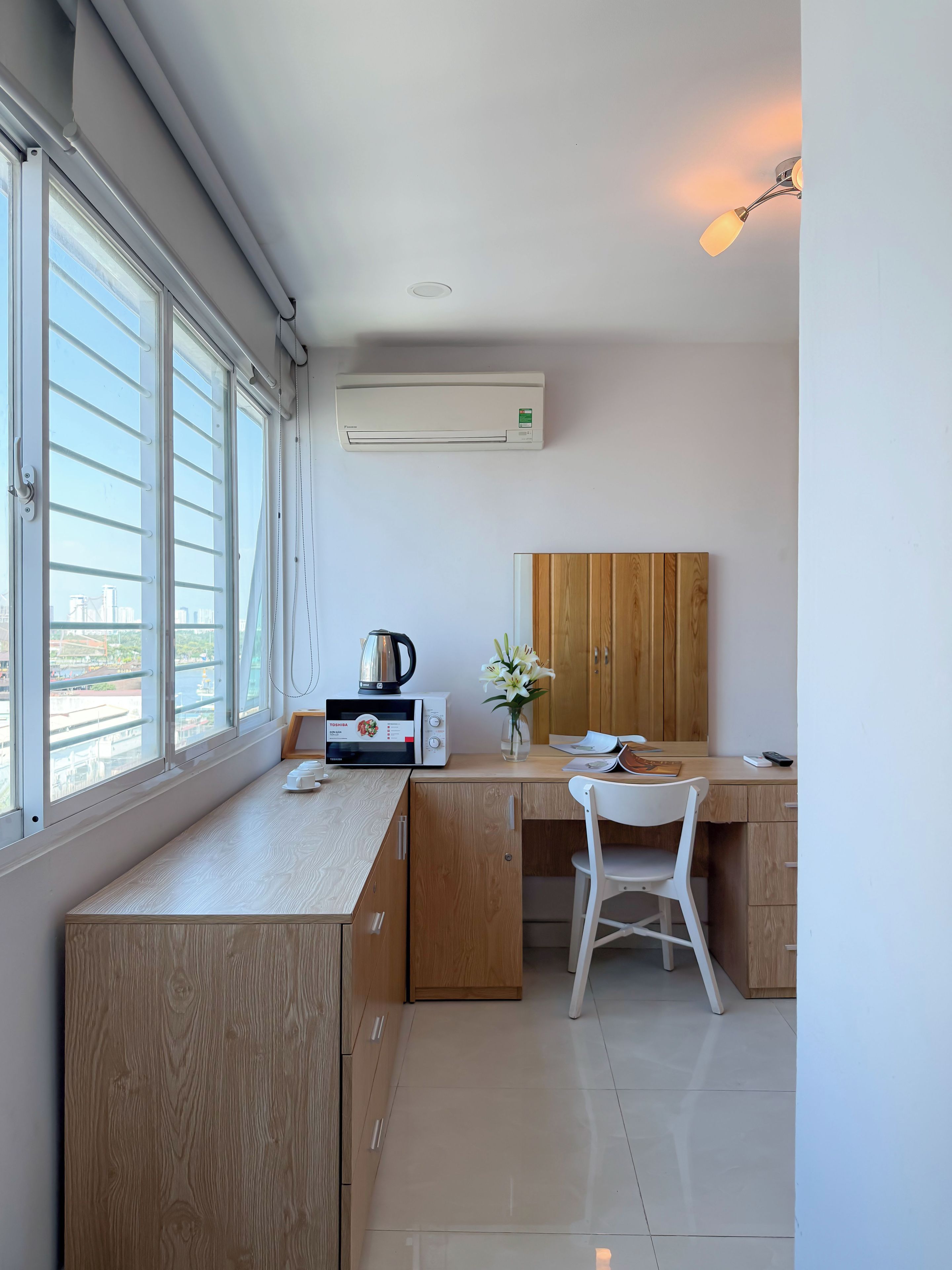 Une cuisine moderne équipée d’un four à micro-ondes encastré, d’une bouilloire et de meubles de rangement en bois.