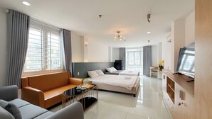 A modern hotel room with a bed, sofa, TV, and a desk. - Quynh Khang Apartments & Hotels (Ho Chi Minh)
