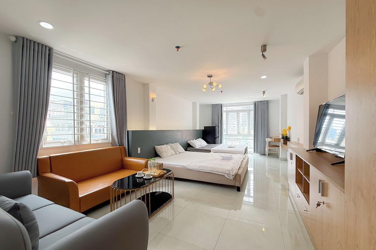 A modern hotel room with a bed, sofa, TV, and a desk.