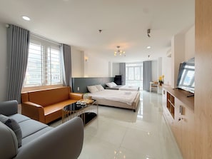 A modern hotel room with a bed, sofa, TV, and a desk. - Quynh Khang Apartments & Hotels (Ho Chi Minh)