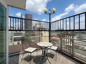 A balcony with a table and chairs, a railing, and a view of the cityscape. - Quynh Khang Apartments & Hotels (Ho Chi Minh)