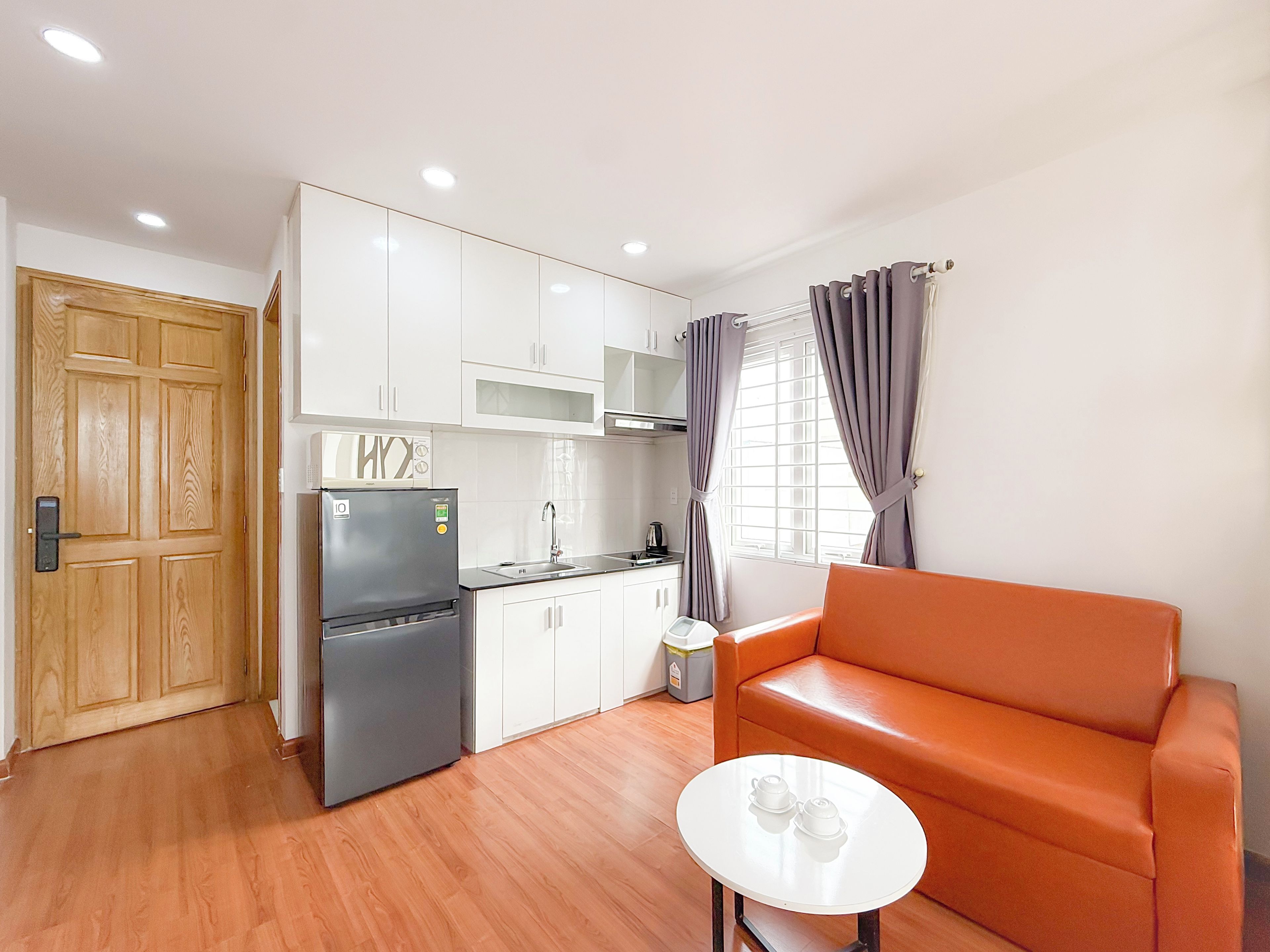 Un espacio habitable compacto con kitchenette, un sofá y una pequeña mesa.