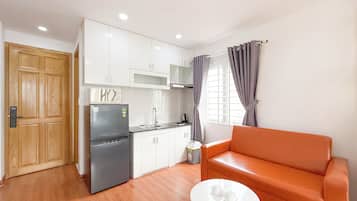 Un espacio habitable compacto con kitchenette, un sofá y una pequeña mesa.