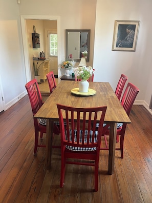 A dining room with a wooden table, red chairs, and a vase of flowers. - Historic 3-bedroom house in downtown Brooklyn Arts district (Wilmington)