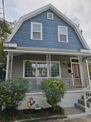 A two-story house with a blue shingled roof, white trim, and a front porch with a red door. - Historic 3-bedroom house in downtown Brooklyn Arts district (Wilmington)