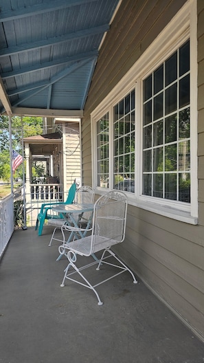 A covered porch with a table and chairs, a view of the street, and a flag. - Historic 3-bedroom house in downtown Brooklyn Arts district (Wilmington)