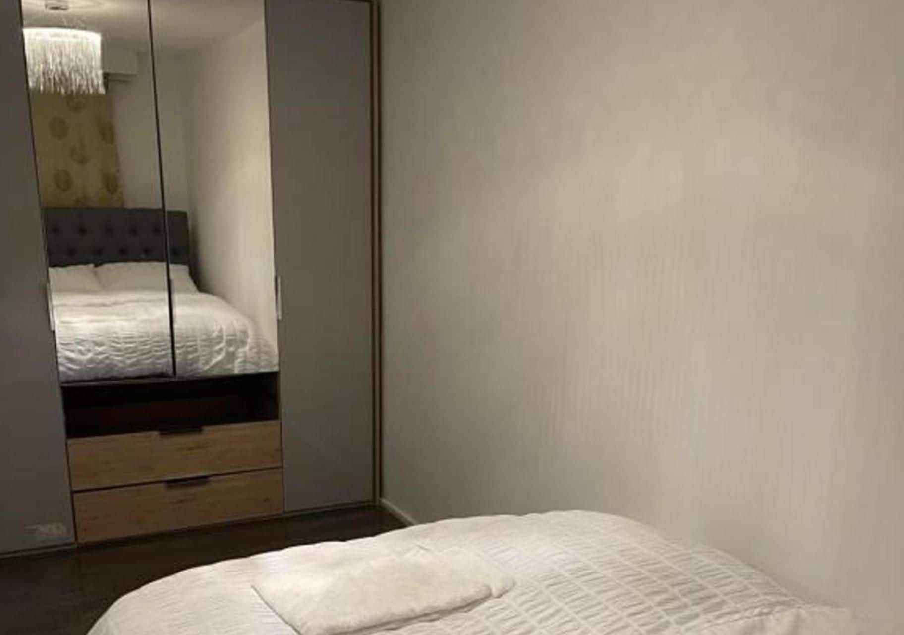 Un dormitorio con cama, armario y espejo.