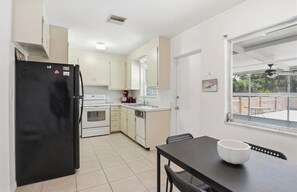 Cocina compacta con refrigerador, horno, pileta y comedor con mesa y sillas.