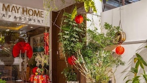 An outdoor seating area with tables and chairs, surrounded by potted plants and hanging decorations. - Omega Hotel (Da Nang Municipality)