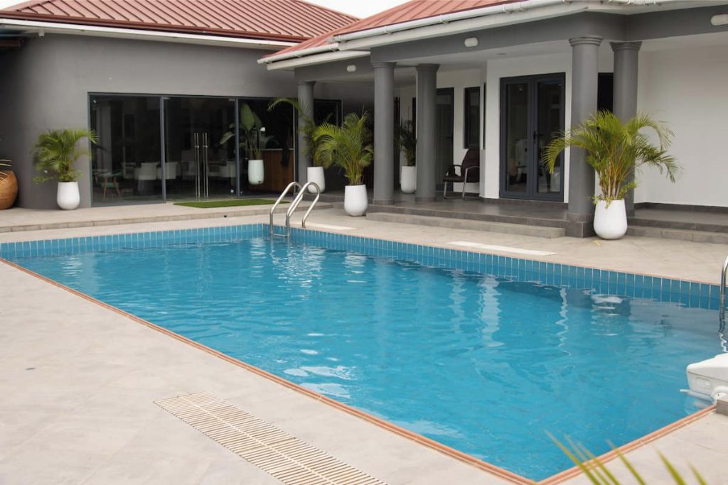 A swimming pool with a clear blue water surface, surrounded by a light-colored tiled deck.