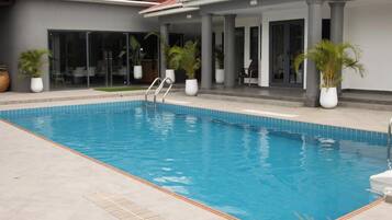 A swimming pool with a clear blue water surface, surrounded by a light-colored tiled deck.
