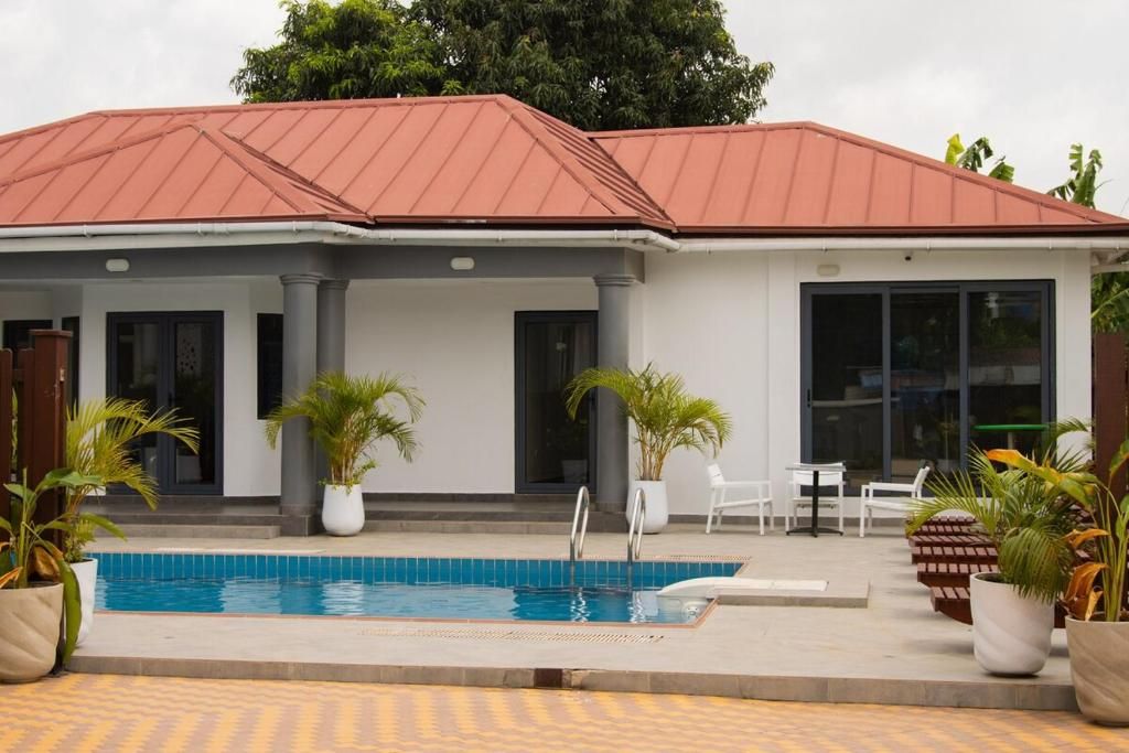 A building with a swimming pool, potted plants, and outdoor seating.