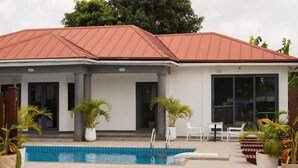 Un edificio con piscina, plantas en macetas y mobiliario de exterior.