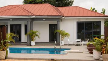 A building with a swimming pool, potted plants, and outdoor seating.
