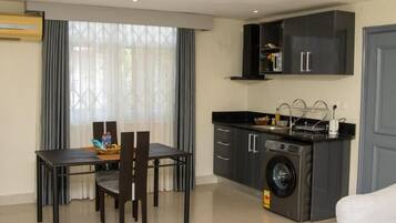 A compact living space with a dining area, kitchen, and a washing machine.