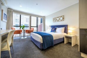 A hotel room with a bed, bedside table, lamp, and a desk with chairs. - U Residence Wellington, BW Signature Collection (Wellington)