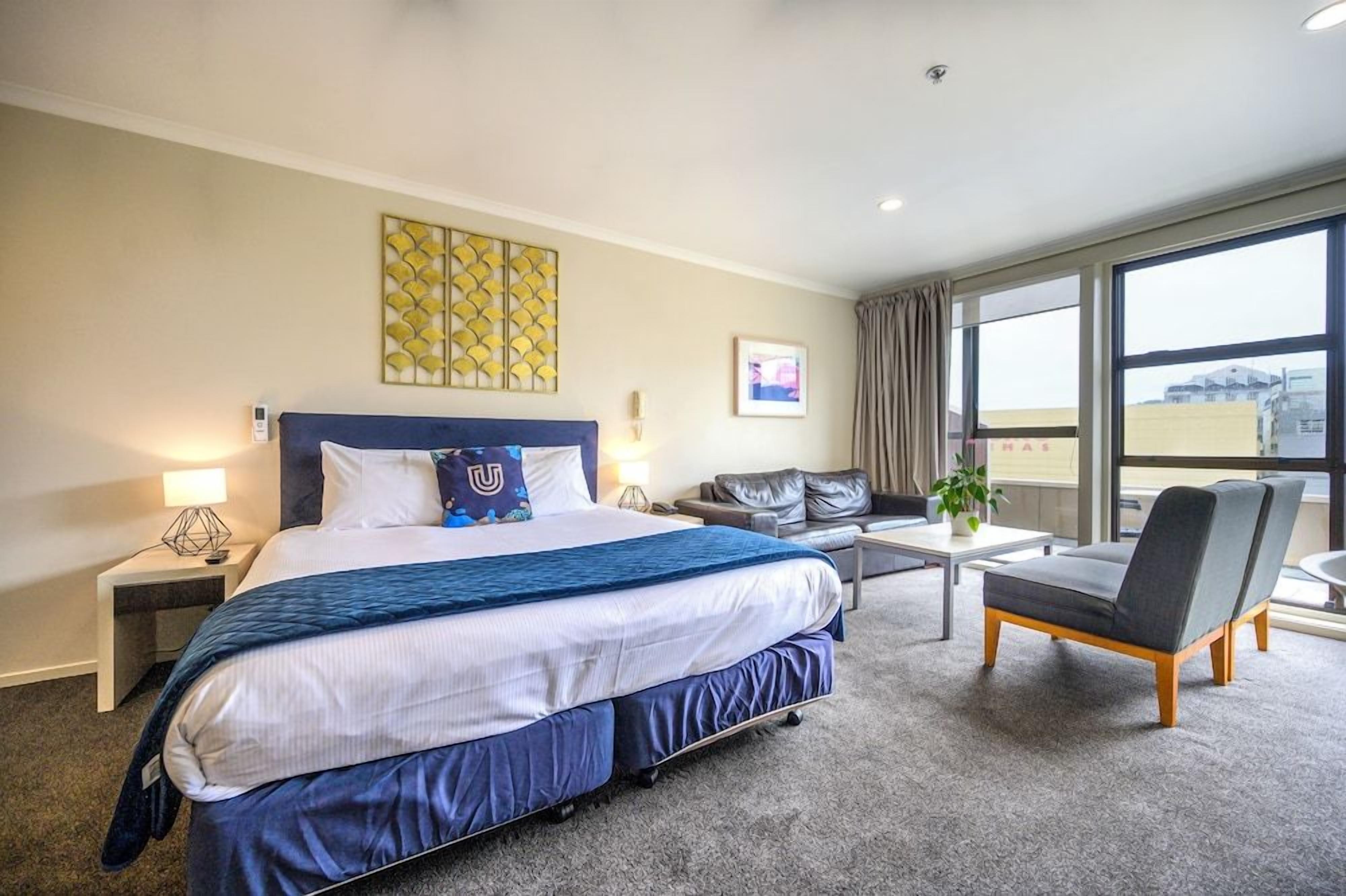 Een hotelkamer met een groot bed, een bank, een stoel, een klein tafeltje en een raam met uitzicht.