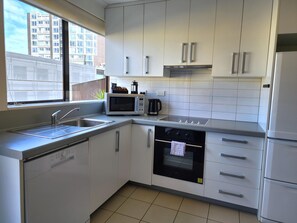 A modern kitchen with white cabinets, a microwave, an oven, and a sink. - U Residence Wellington, BW Signature Collection (Wellington)