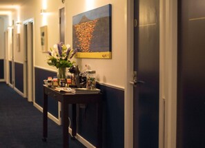 A hotel hallway with a reception desk, a vase with flowers, and a painting on the wall. - U Residence Wellington, BW Signature Collection (Wellington)