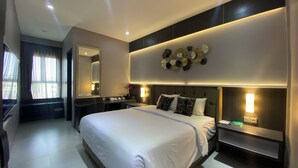 A modern hotel room with a large bed, bedside tables, a mirror, and decorative wall art.
