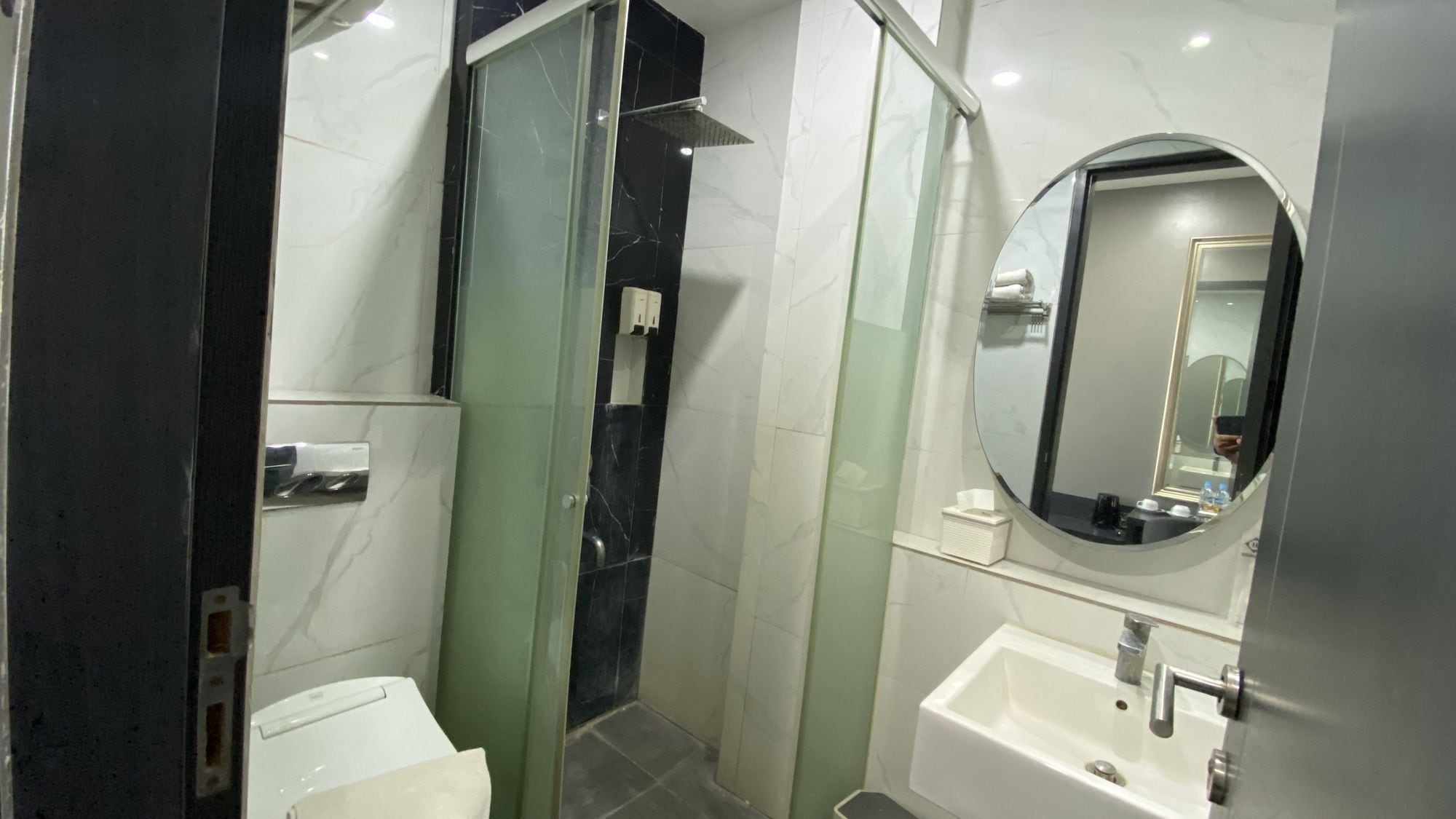 Un baño moderno con ducha acristalada, lavamanos blanco y espejo.