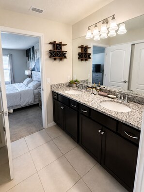 Un baño moderno con lavamanos doble, muebles oscuros y un espejo grande.