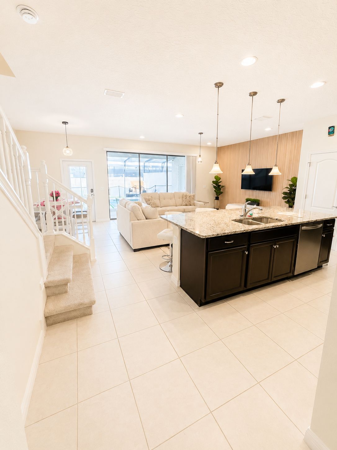 A modern kitchen with a central island, pendant lighting, and a large window providing natural light.