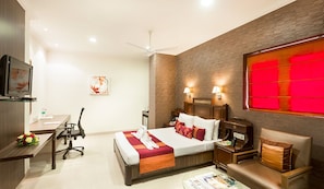 A hotel room with a bed, desk, chair, and a television. - The Lotus Service Apartments (Chennai)