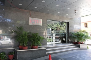 A building entrance with a sign reading 'LOTUS' and potted plants on the steps. - The Lotus Service Apartments (Chennai)