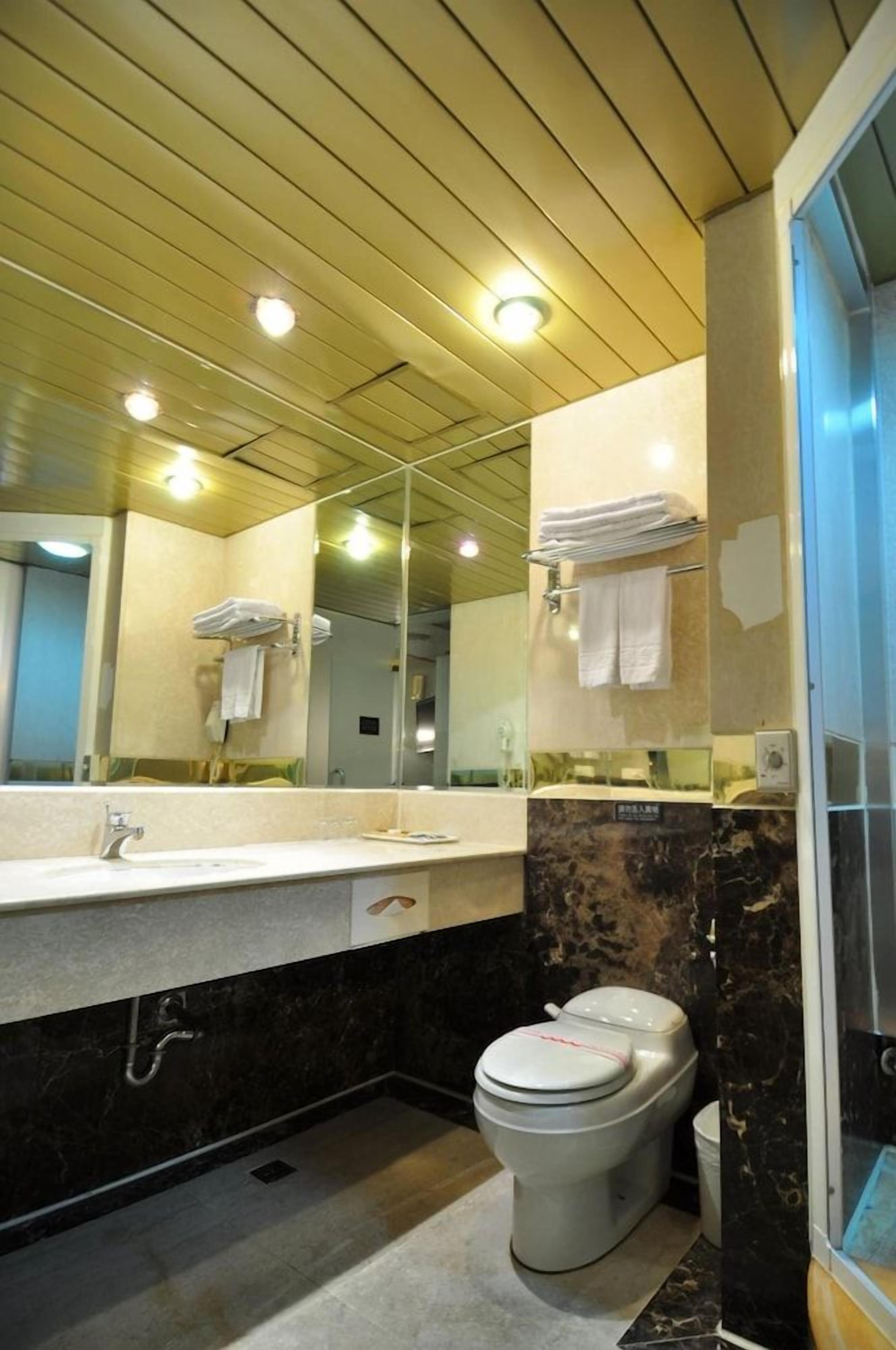 A modern bathroom with a large mirror, a sink, a toilet, and a shower area.