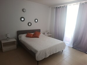 Una camera da letto con un letto, comodini, una lampada e una finestra con tende.