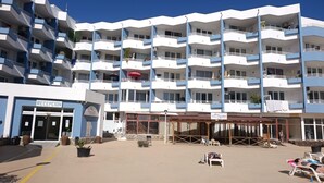 Et hotel med flere etager, en reception, udendørs siddepladser og balkoner.