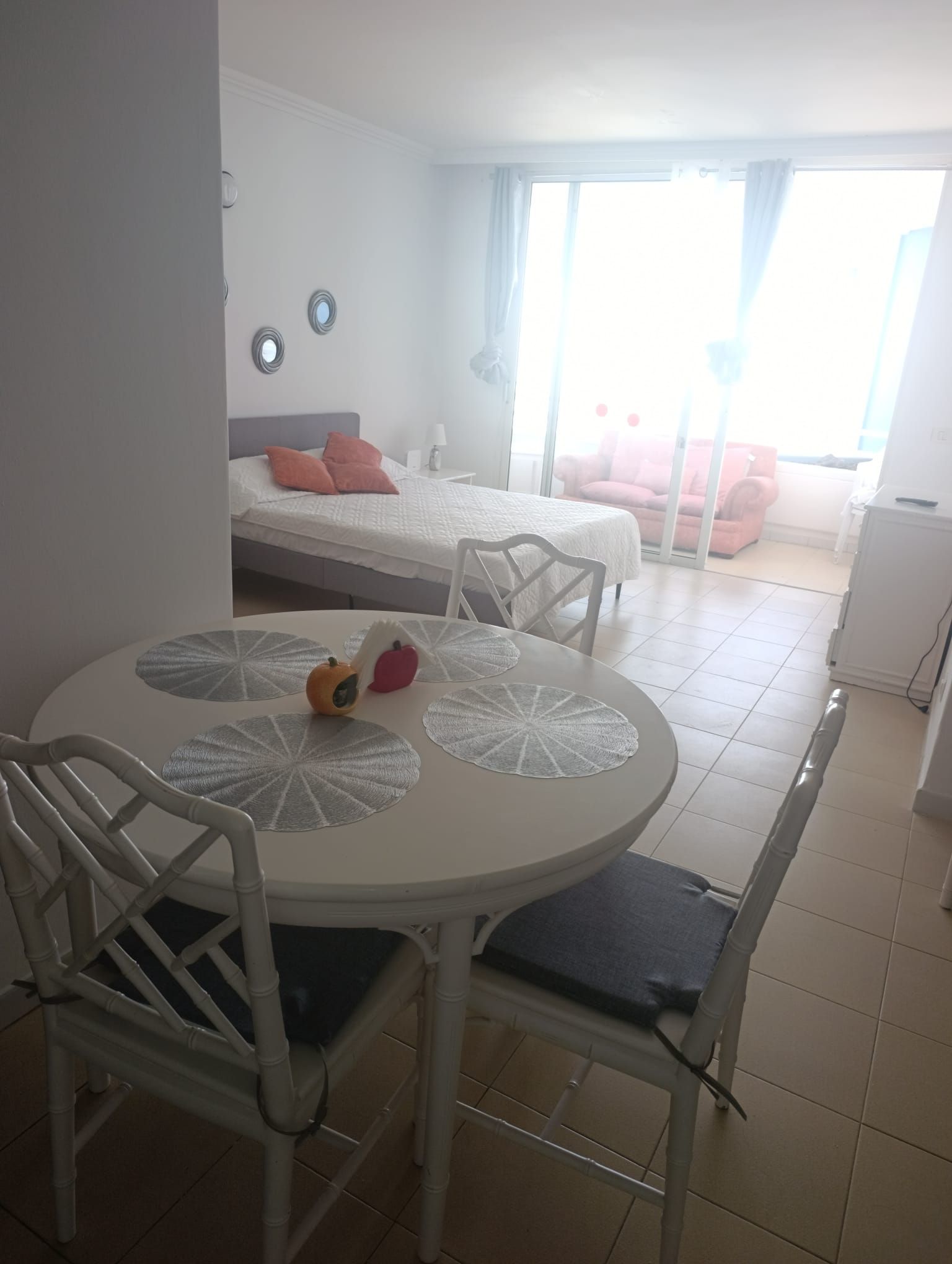 Ein Hotelzimmer mit Esstisch, Stühlen, einem Bett, einer Couch und Blick ins Freie.
