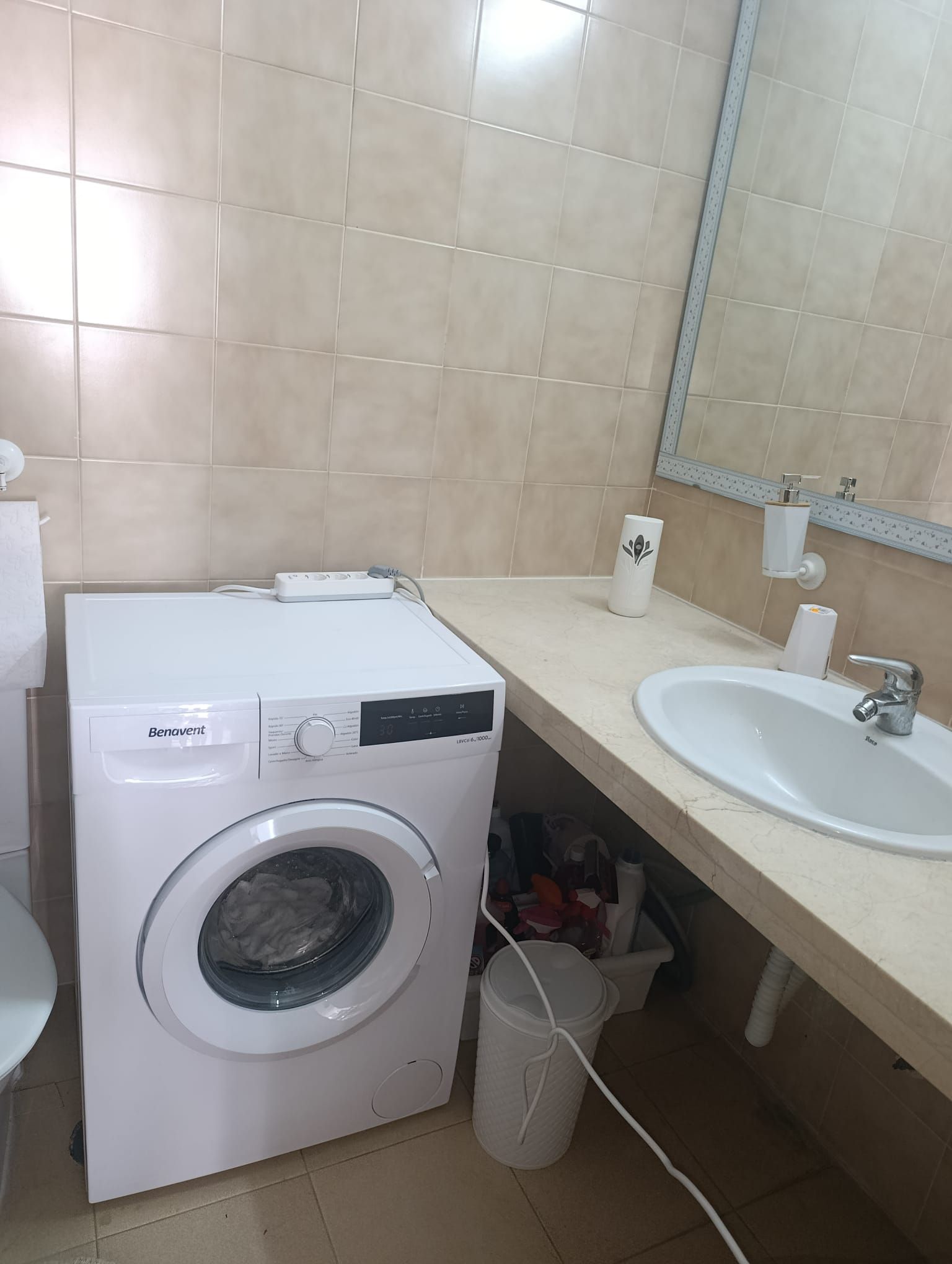 Une machine à laver Benavent dans une salle de bain équipée d’un lavabo et d’un miroir.