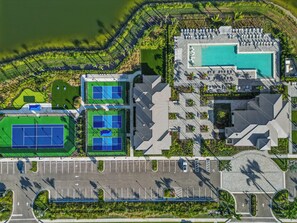 Luftaufnahme eines Resorts mit Schwimmbad, Tennisplätzen und einem Parkplatz.